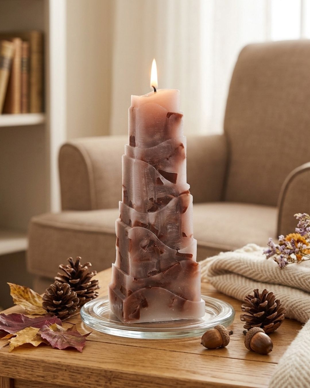 Braune handgegossene Designkerze mit Zapfen und Herbstlaub im Wohnzimmer