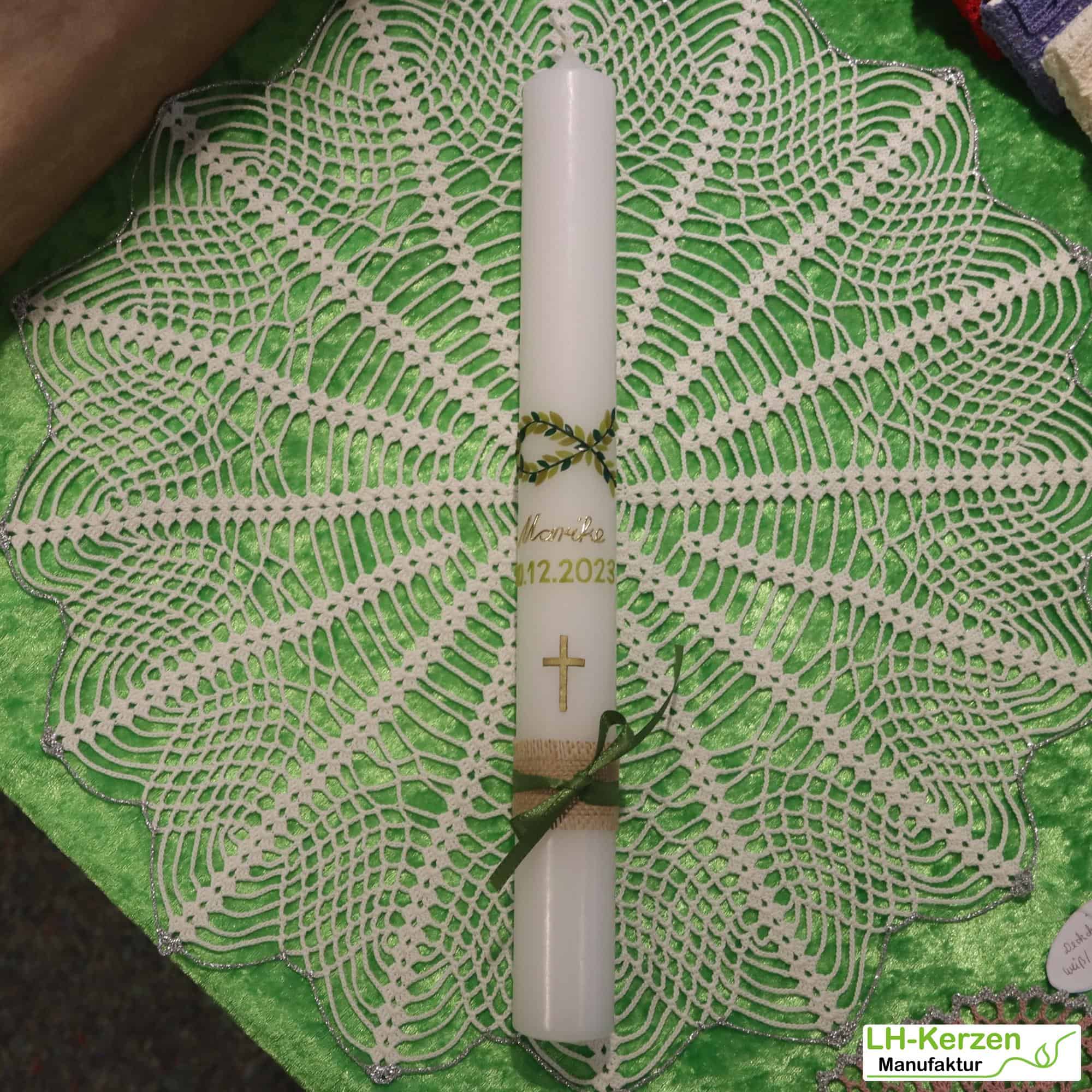Schlanke Taufkerze mit zu einem Fisch geformter grüner Blattranke und goldenem Kreuz
