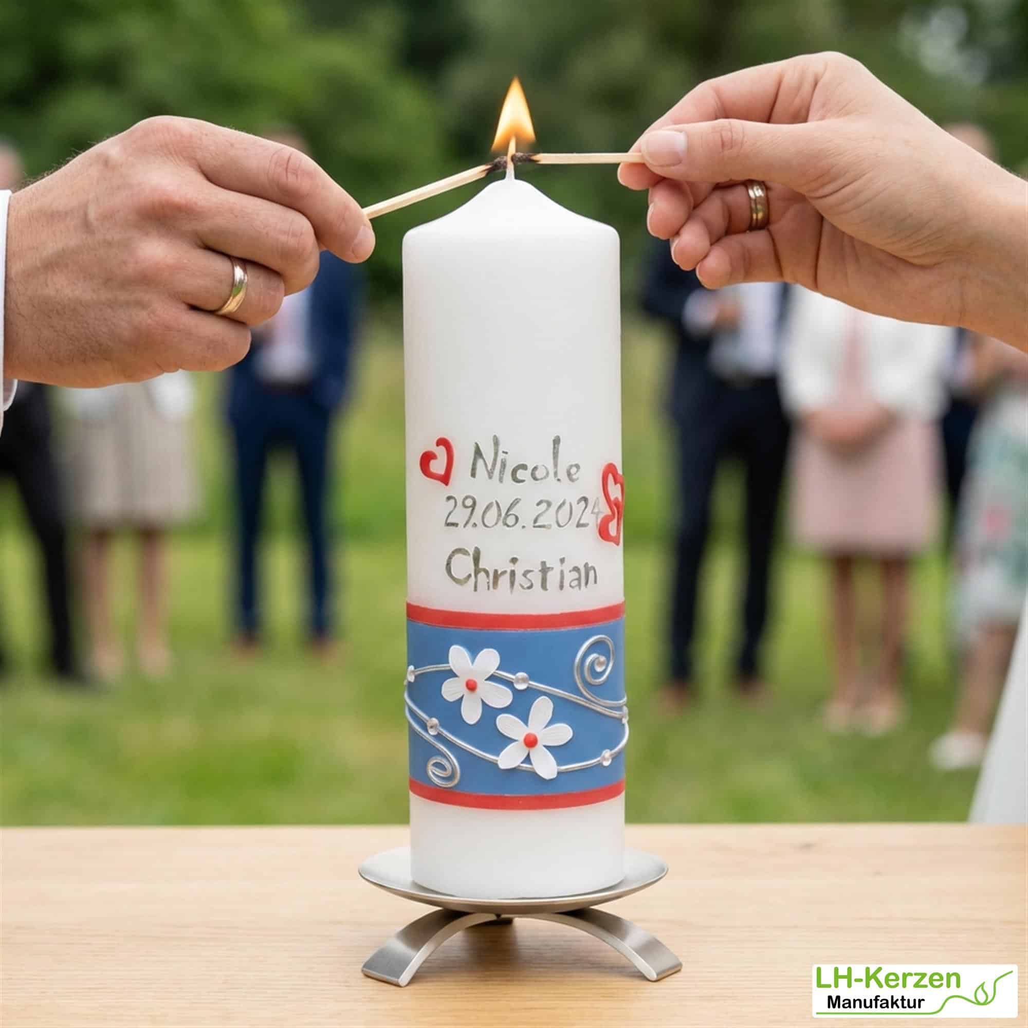 Hochzeitskerze mit weißen Blumen, blauem Band und Ringen