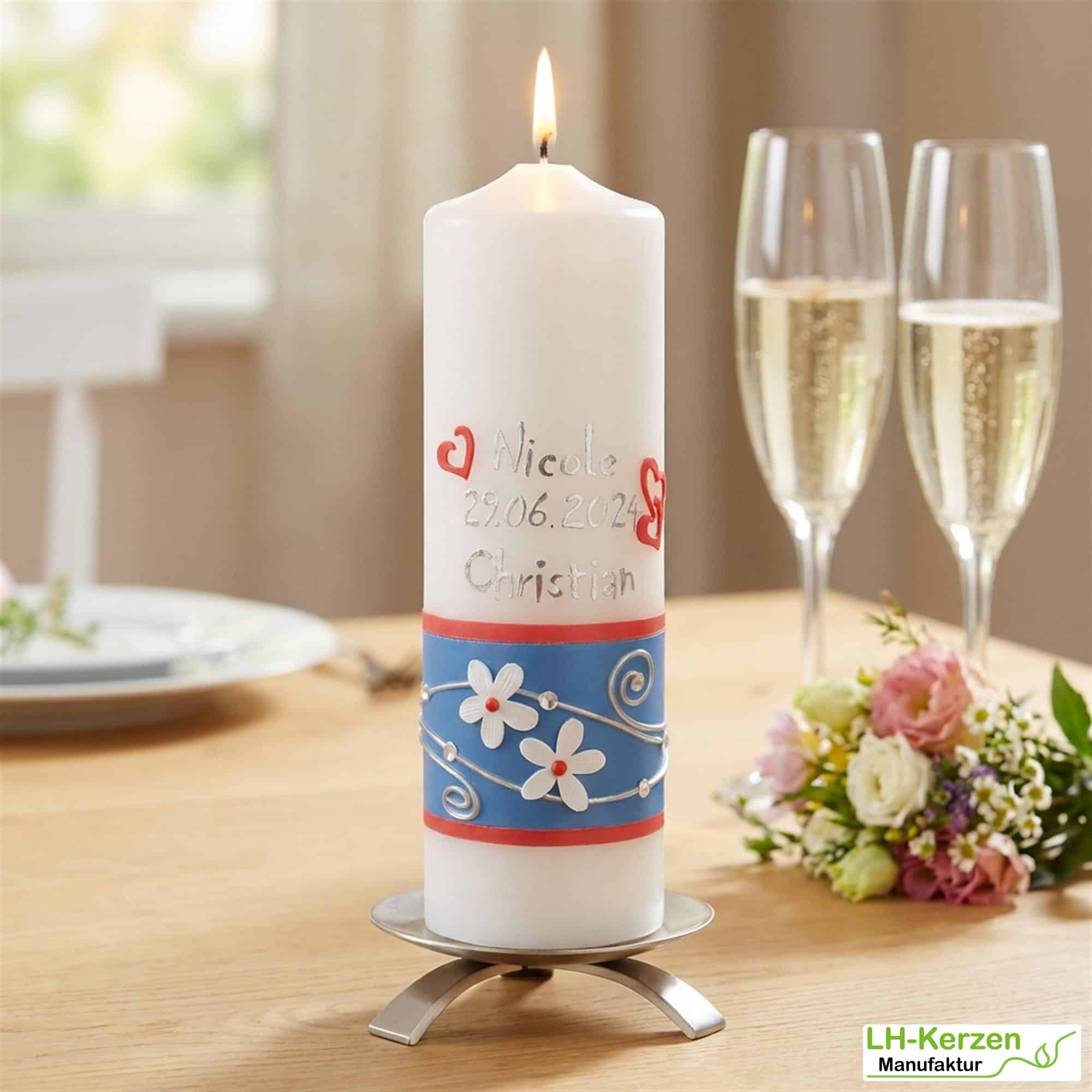 Hochzeitskerze mit weißen Blumen, blauem Band und Ringen
