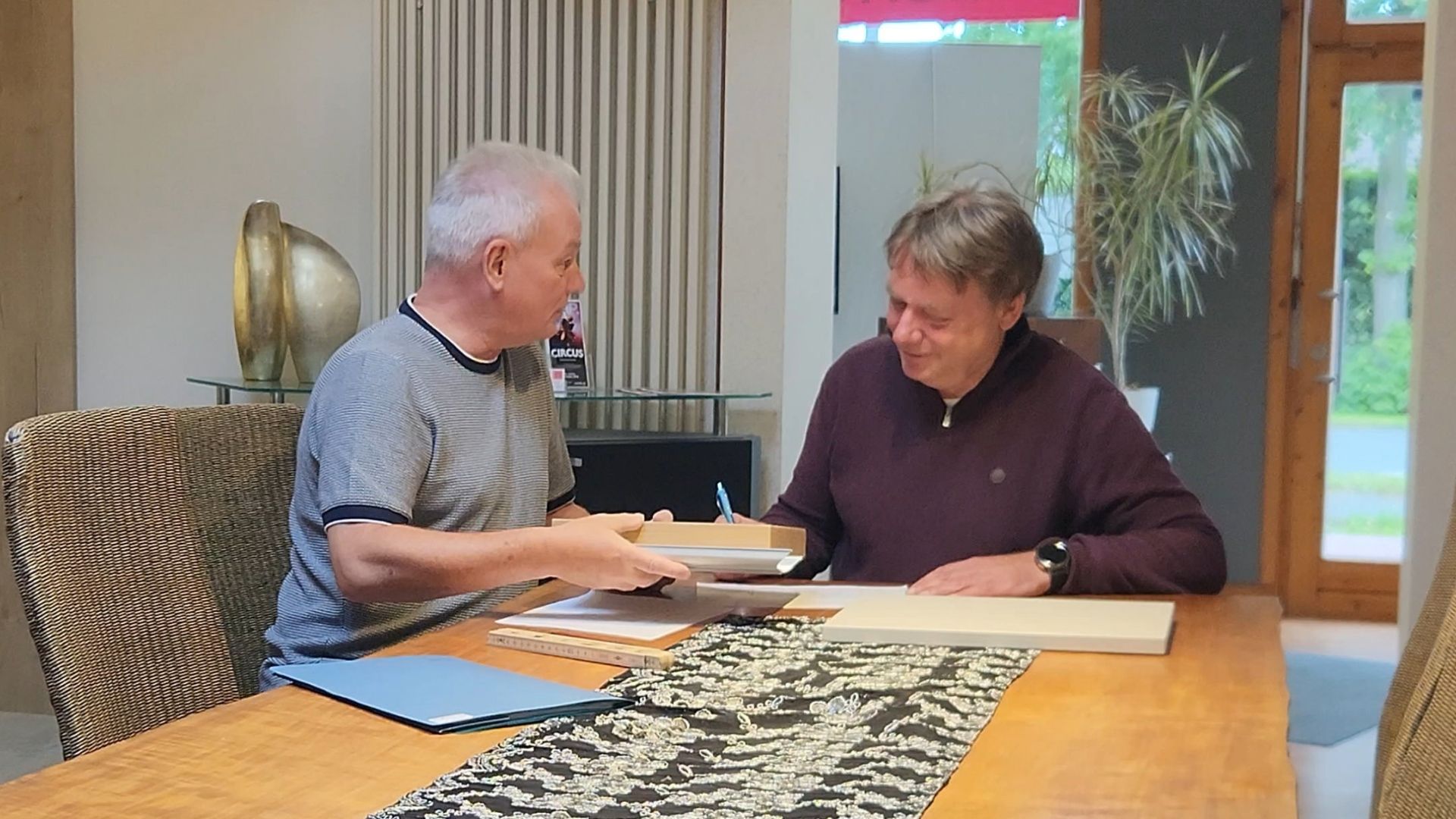 Zwei Männer besprechen an einem Tisch Pläne und Materialmuster für eine individuelle Einrichtung.