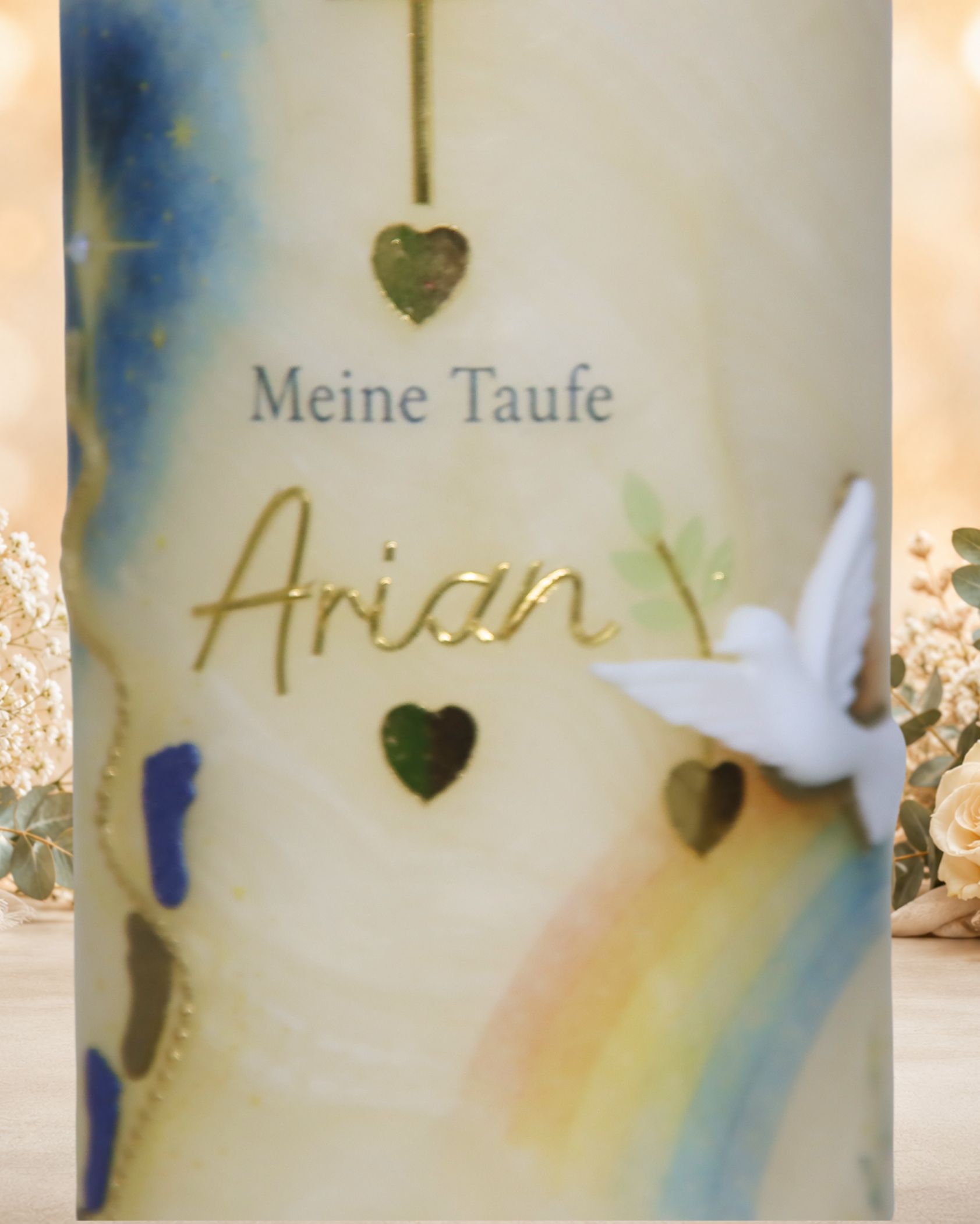 Detail einer personalisierten Taufkerze mit dem Namen Arian, goldenen Herzen und plastischer weißer Taube